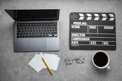 Photo of Flat lay composition with movie clapper and laptop on grey textured table