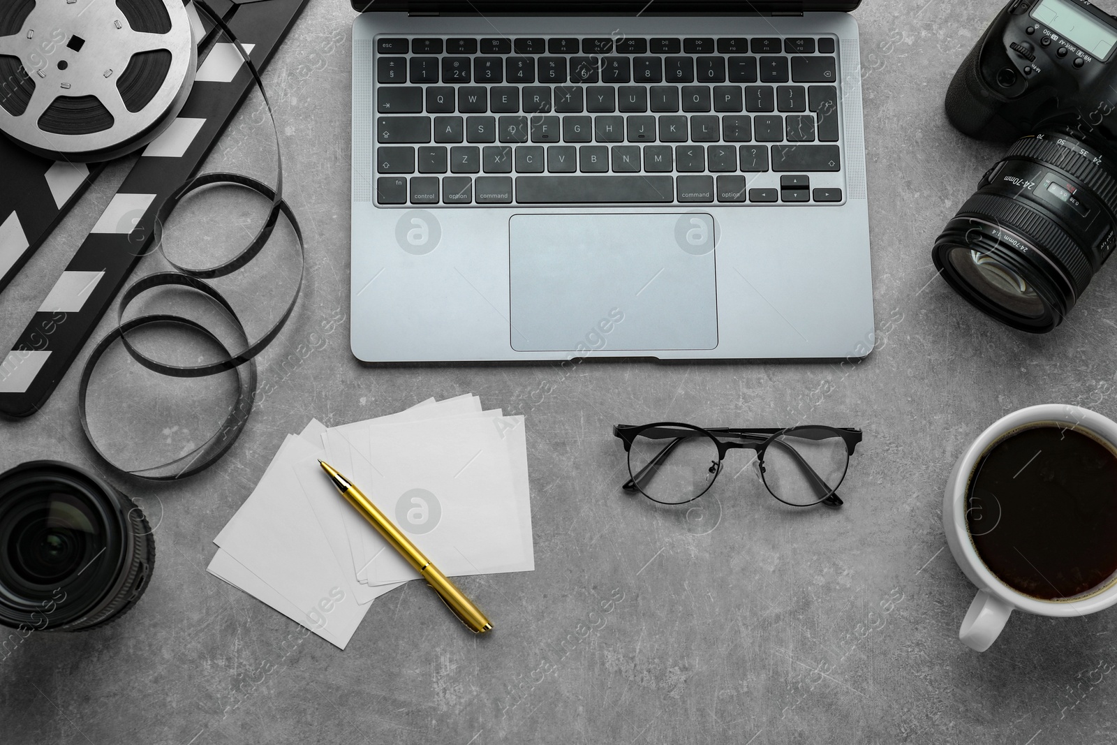 Photo of Flat lay composition with camera, film reel and laptop on grey textured table