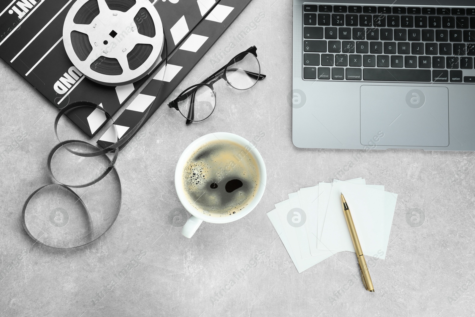 Photo of Flat lay composition with movie clapper, film reel and laptop on grey textured table