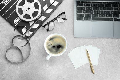 Photo of Flat lay composition with movie clapper, film reel and laptop on grey textured table