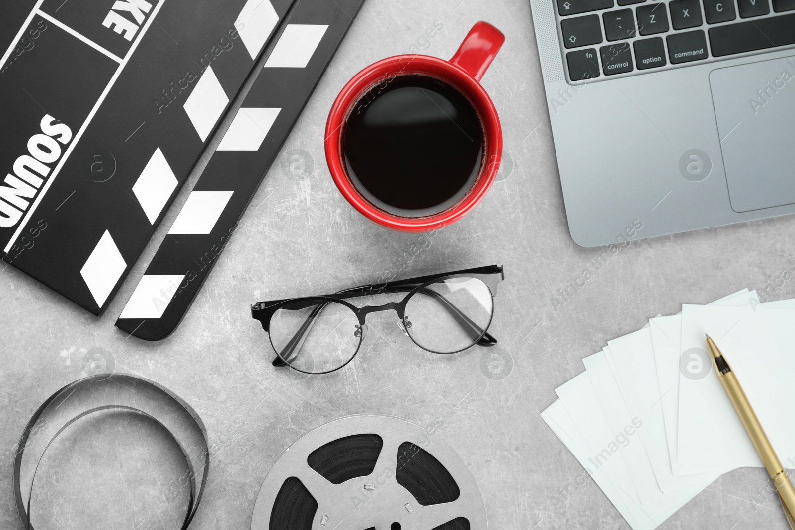 Photo of Flat lay composition with movie clapper, film reel and laptop on grey textured table