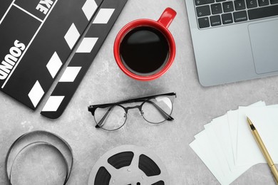 Photo of Flat lay composition with movie clapper, film reel and laptop on grey textured table