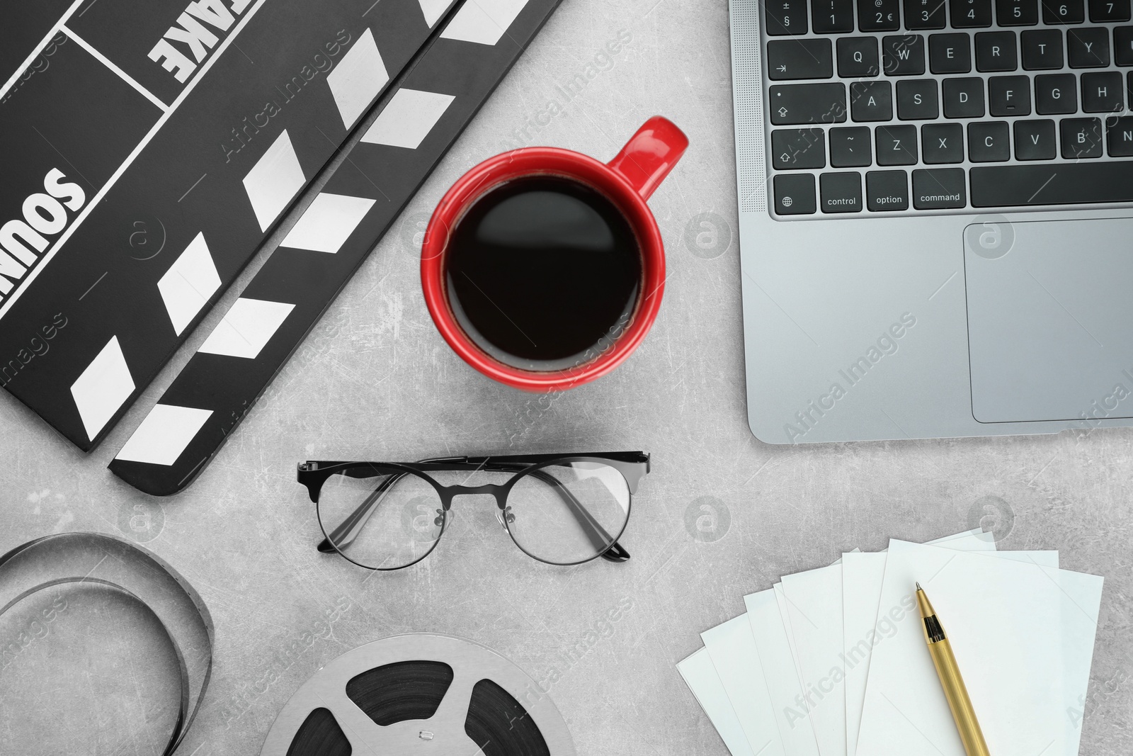 Photo of Flat lay composition with movie clapper, film reel and laptop on grey textured table