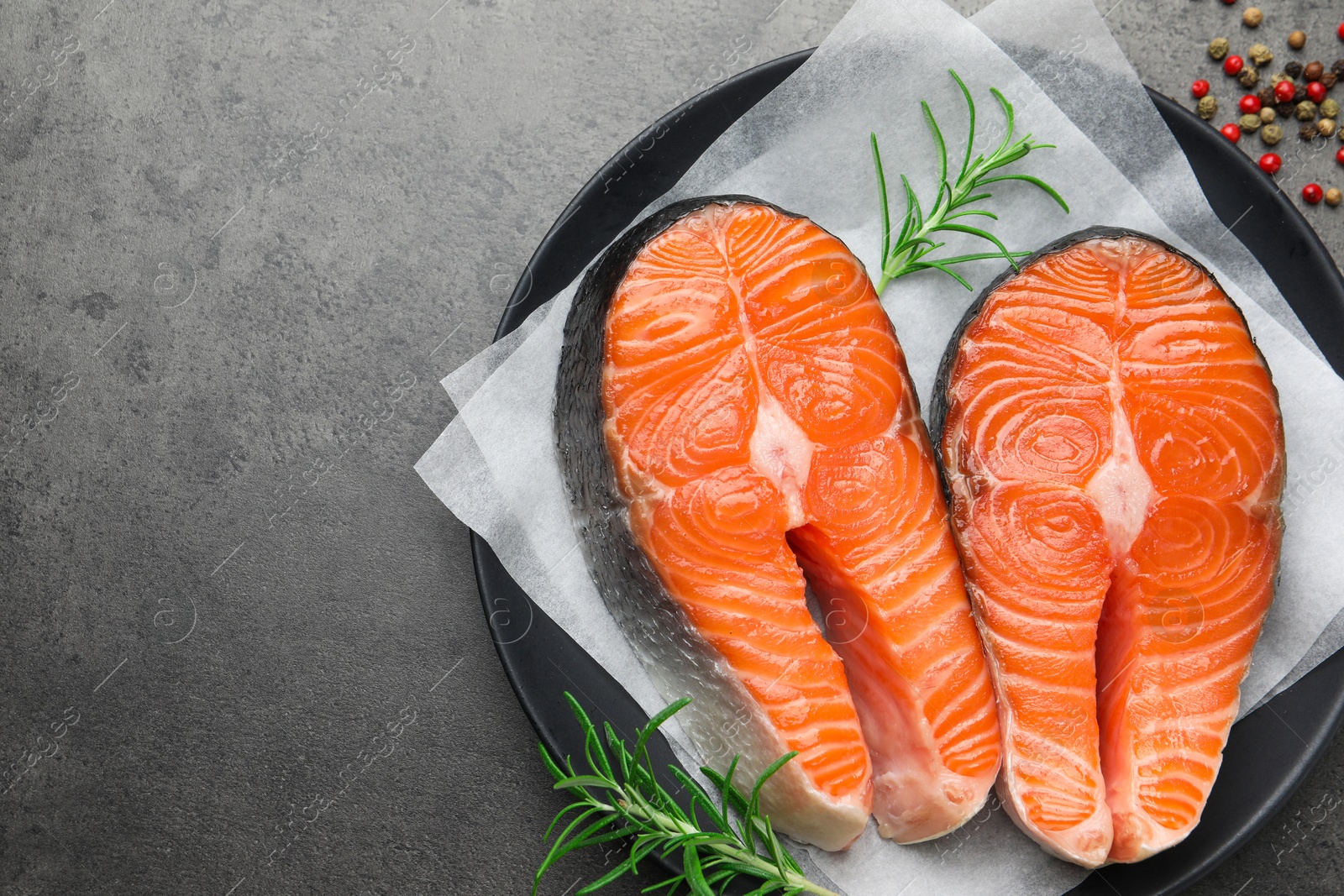 Photo of Fresh raw salmon steaks and spices on grey textured table, top view. Space for text