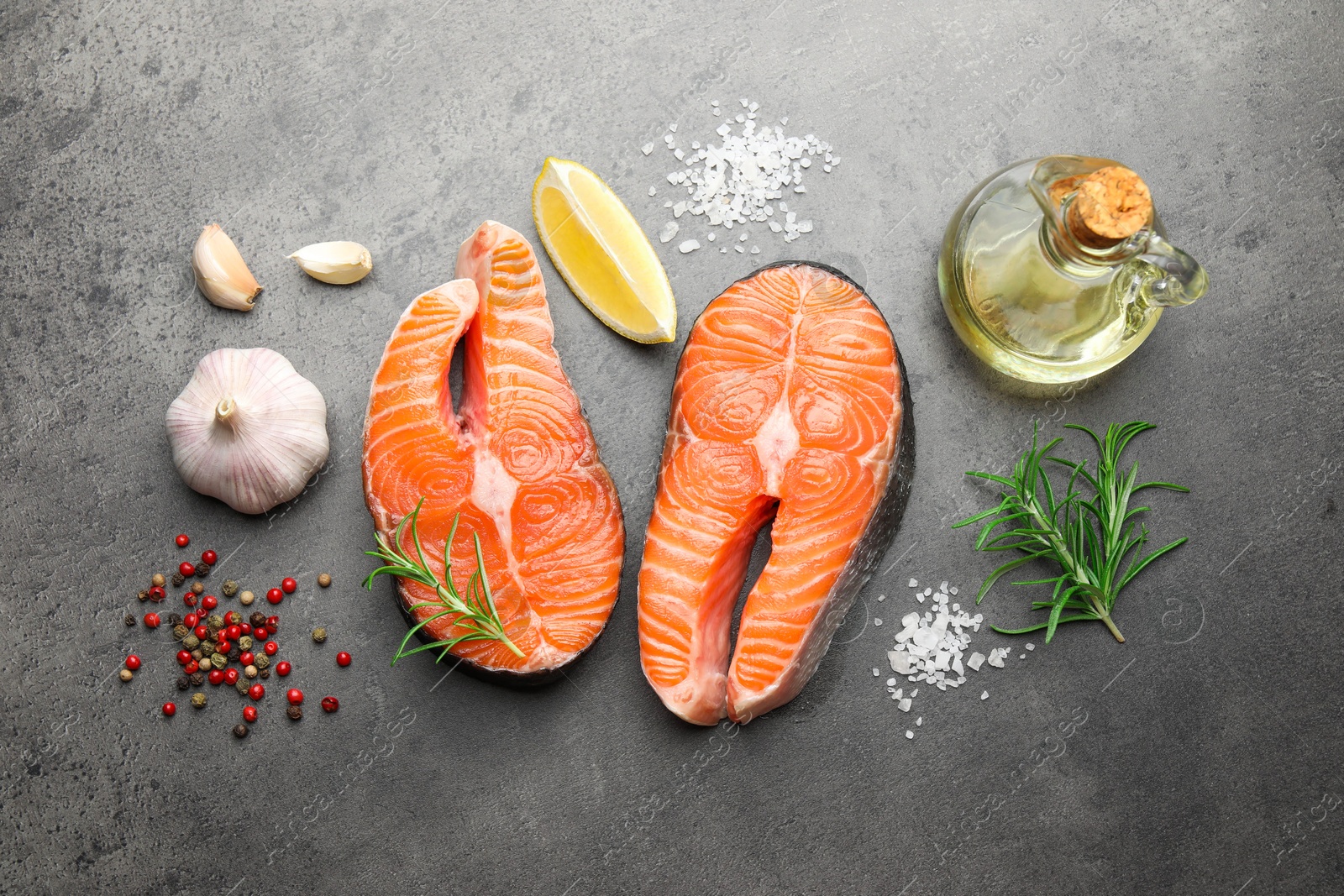 Photo of Fresh raw salmon steaks and spices on grey textured table, flat lay