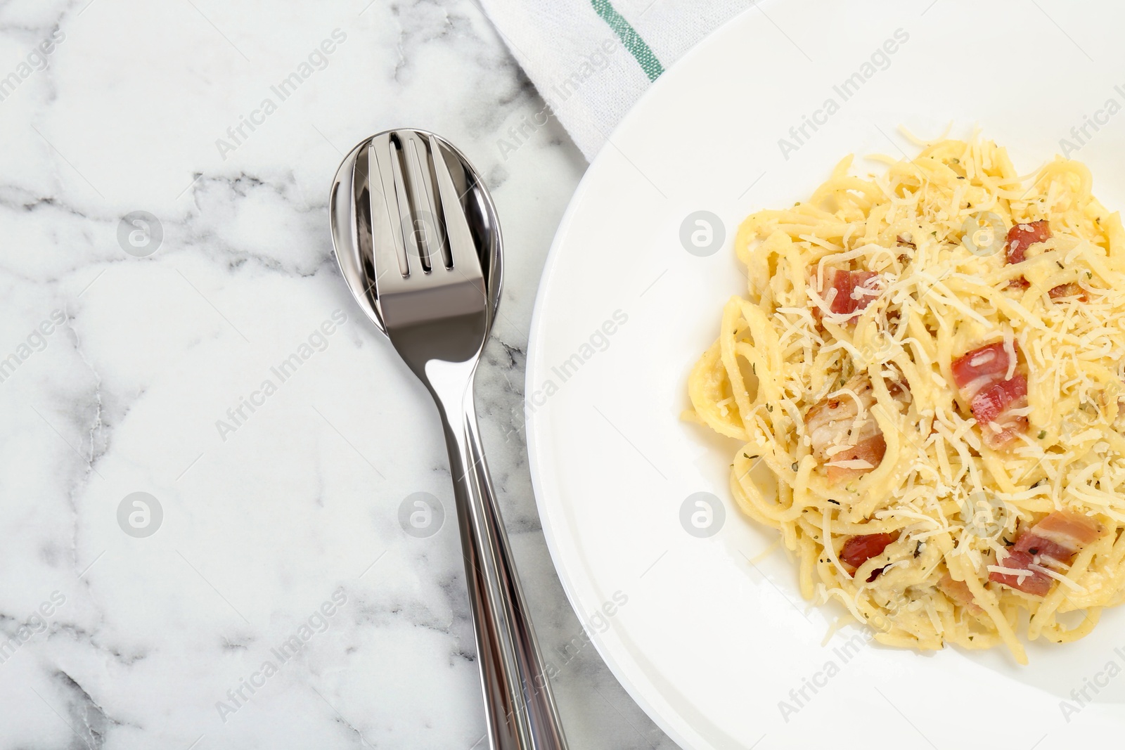 Photo of Delicious pasta Carbonara with bacon served on white marble table, flat lay