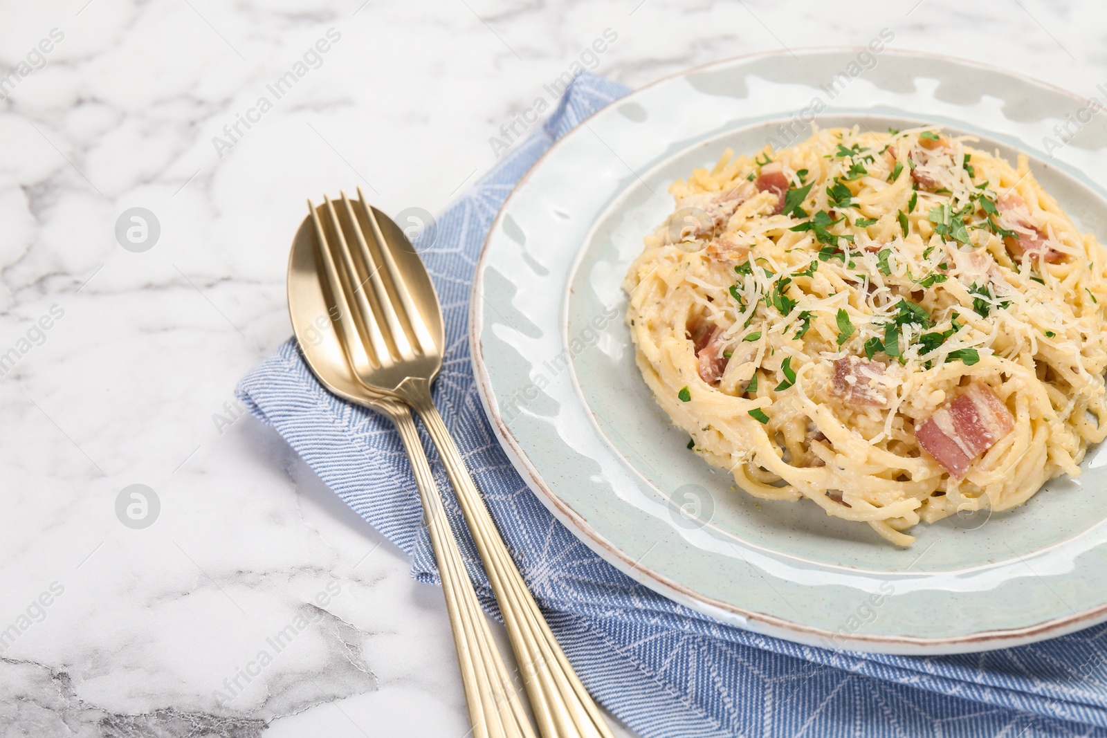 Photo of Delicious pasta Carbonara with bacon served on white marble table, closeup