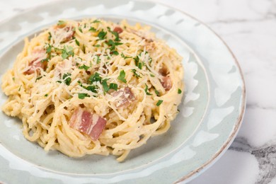 Photo of Delicious pasta Carbonara with bacon on white marble table, closeup