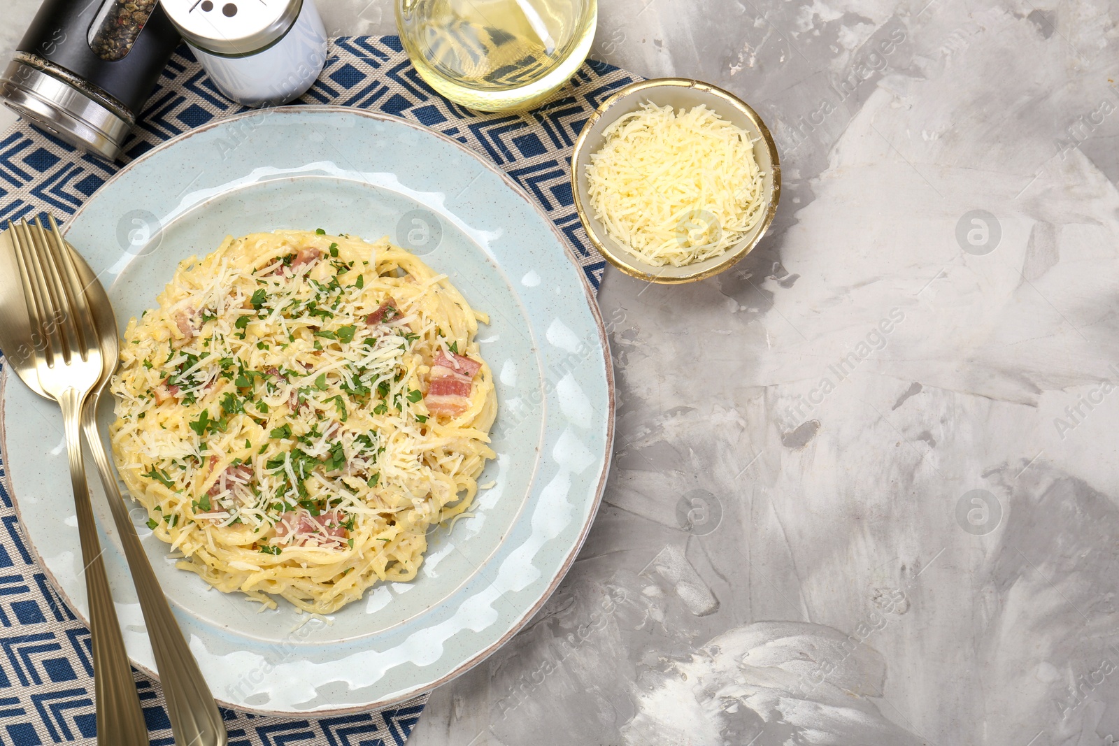 Photo of Delicious pasta Carbonara with bacon served on gray textured table, flat lay. Space for text