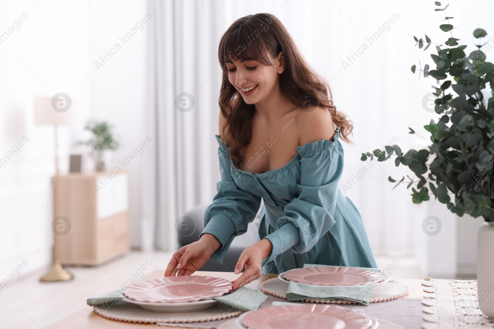 Photo of Woman setting table for dinner at home