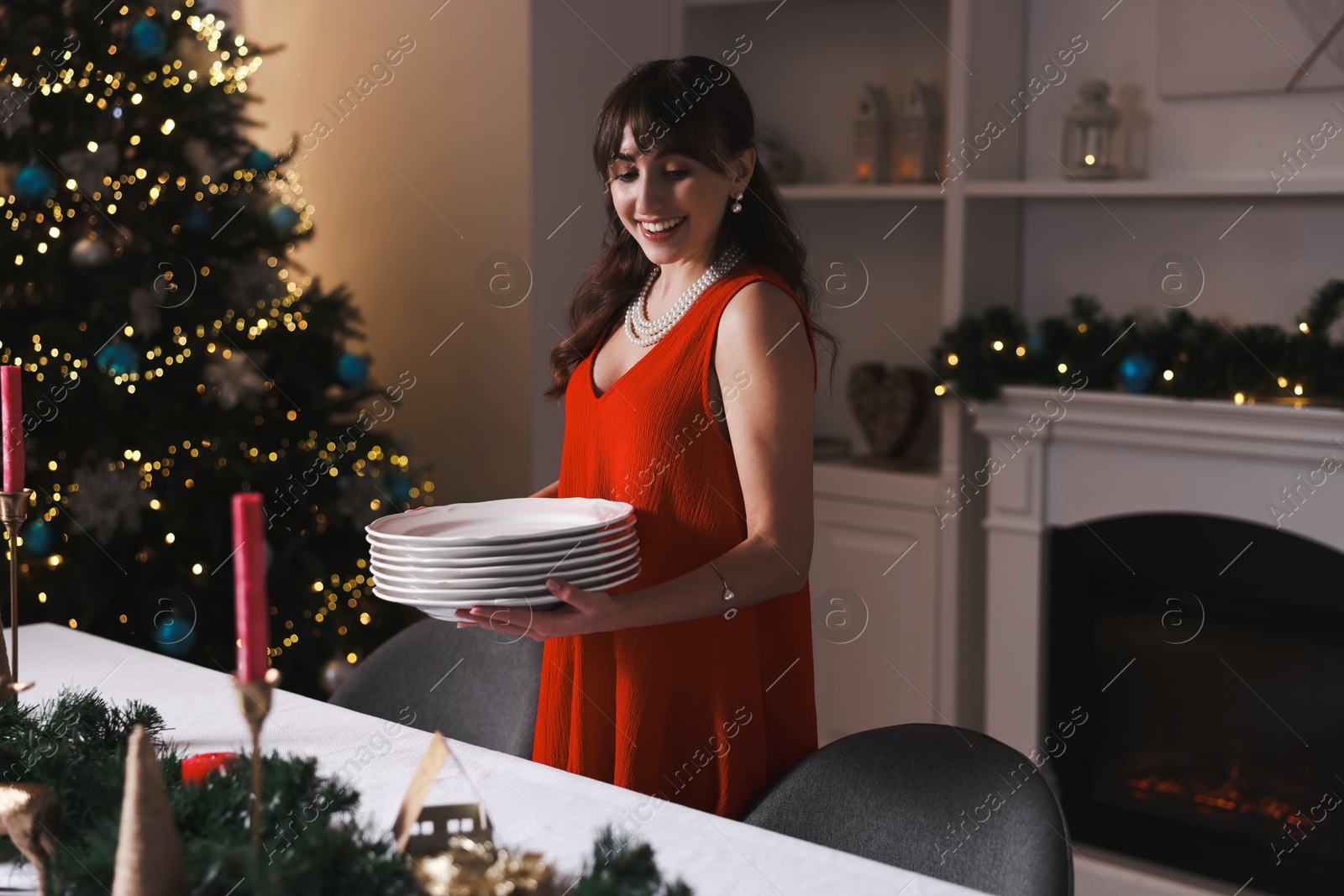 Photo of Woman setting table for Christmas dinner at home