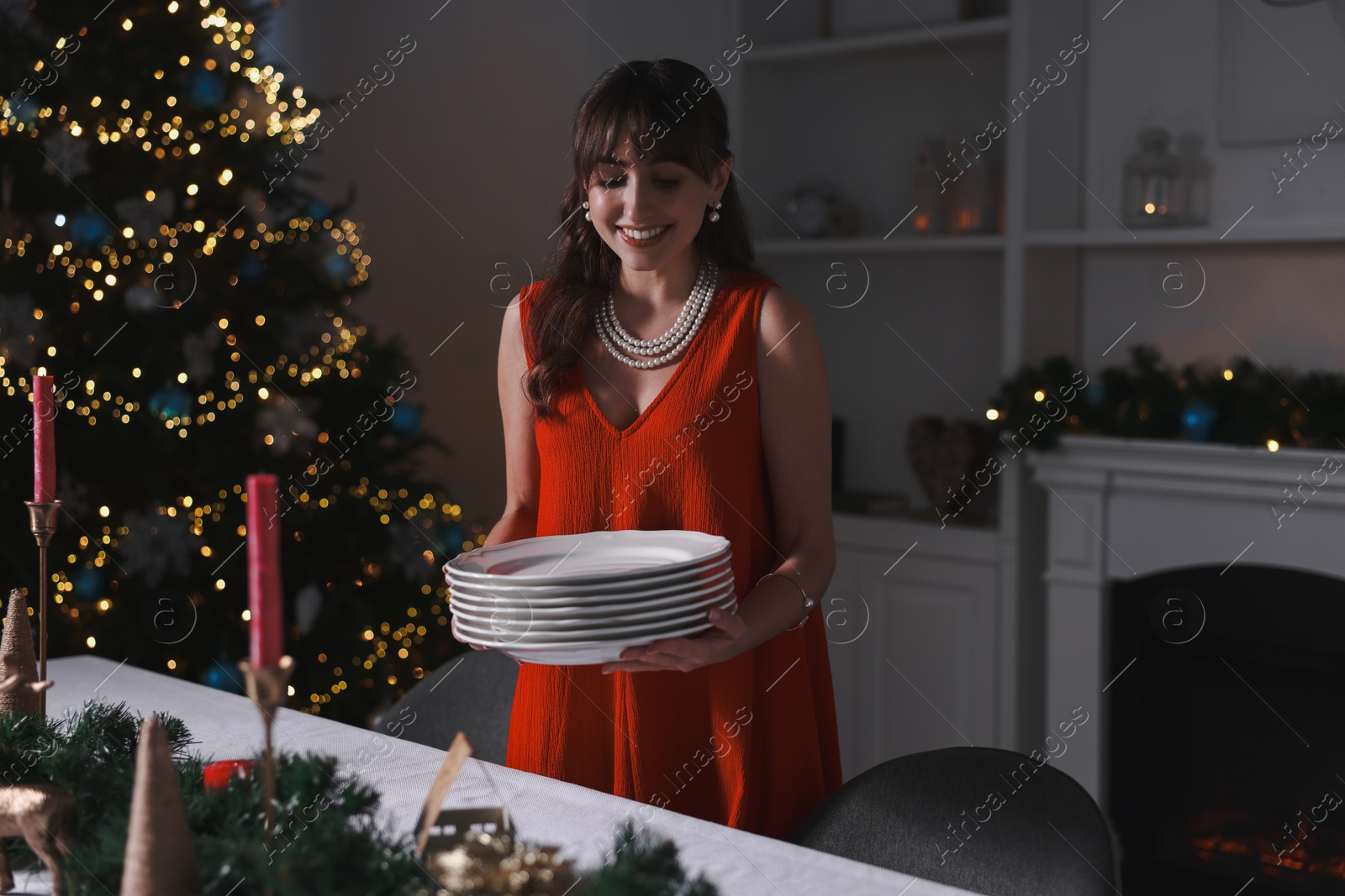 Photo of Woman setting table for Christmas dinner at home