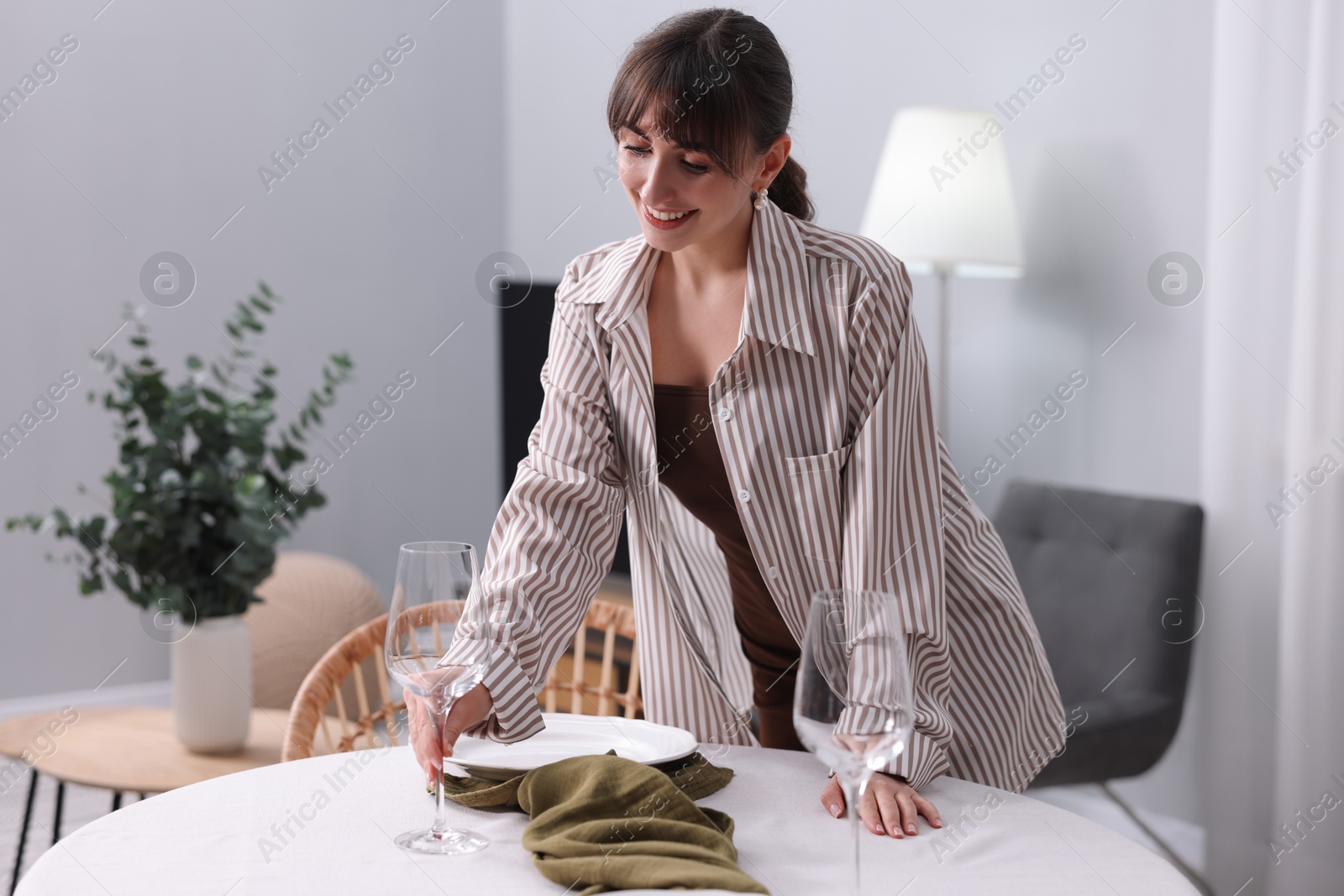 Photo of Woman setting table for dinner at home