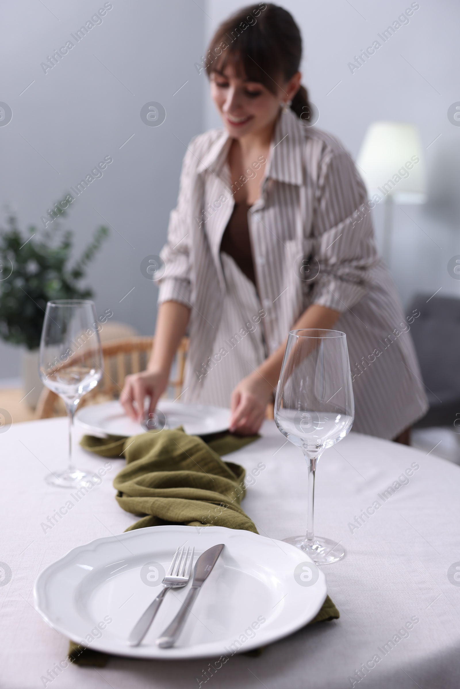 Photo of Woman setting table for dinner at home, selective focus