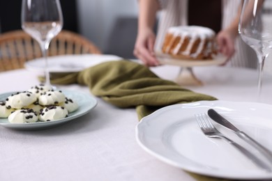 Photo of Woman setting table for dinner at home, focus on plate and cutlery