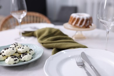 Photo of Festive table setting with dishware, cutlery, desserts and glasses indoors, closeup