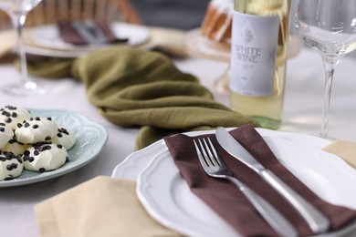 Photo of Festive table setting with dishware, cutlery, desserts and wine indoors, closeup