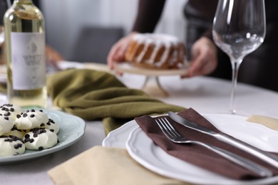 Photo of Woman setting table for dinner at home, focus on plate and cutlery