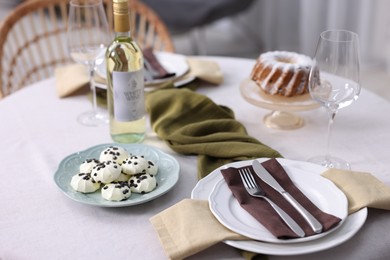 Photo of Festive table setting with dishware, desserts, wine and glasses indoors