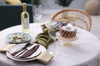 Photo of Festive table setting with dishware, desserts, wine and glasses indoors