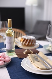 Photo of Festive table setting with dishware, cutlery, desserts and wine indoors