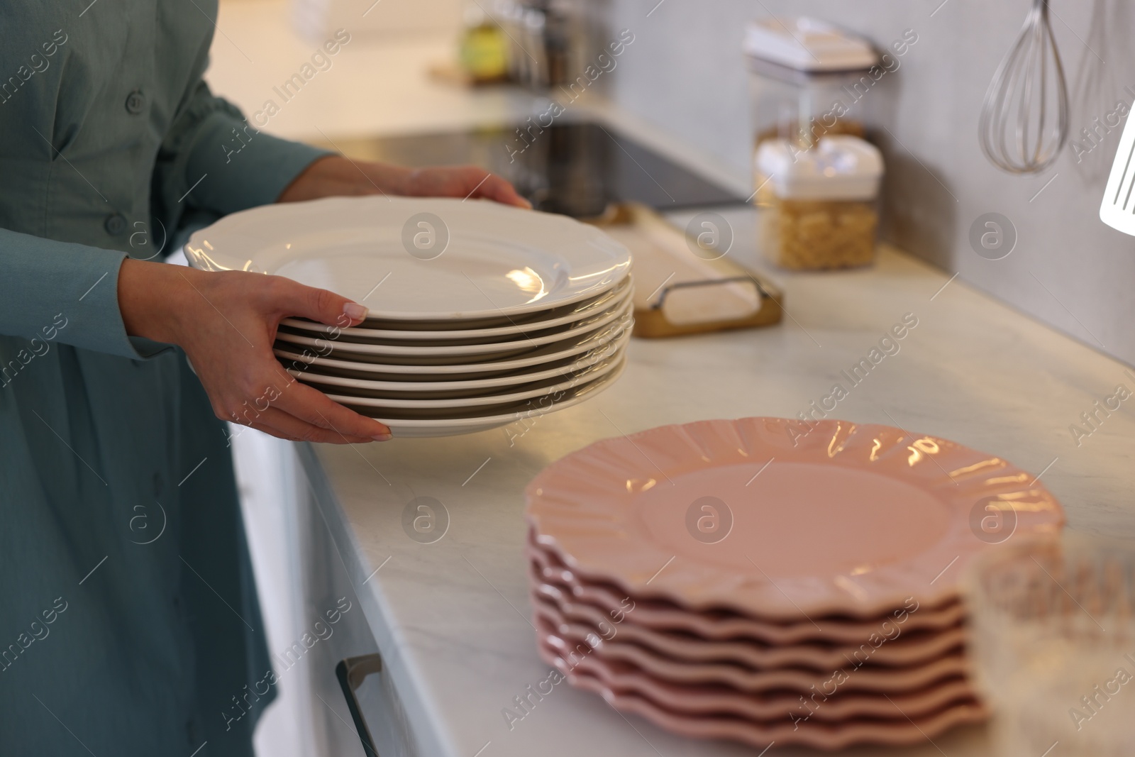 Photo of Woman with plates near countertop in kitchen, closeup