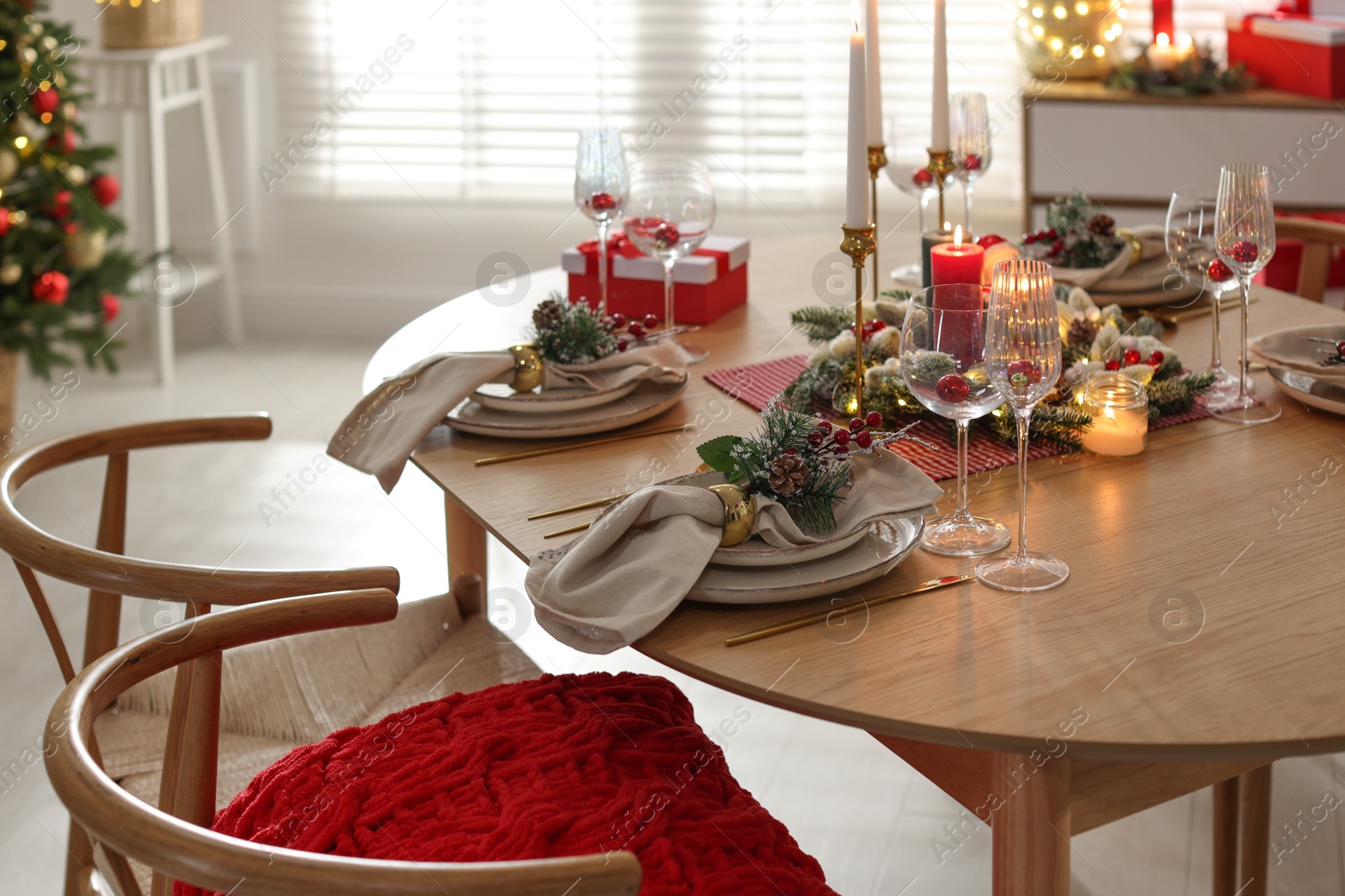 Photo of Christmas celebration. Festive table setting with dishware, glasses and decor in room