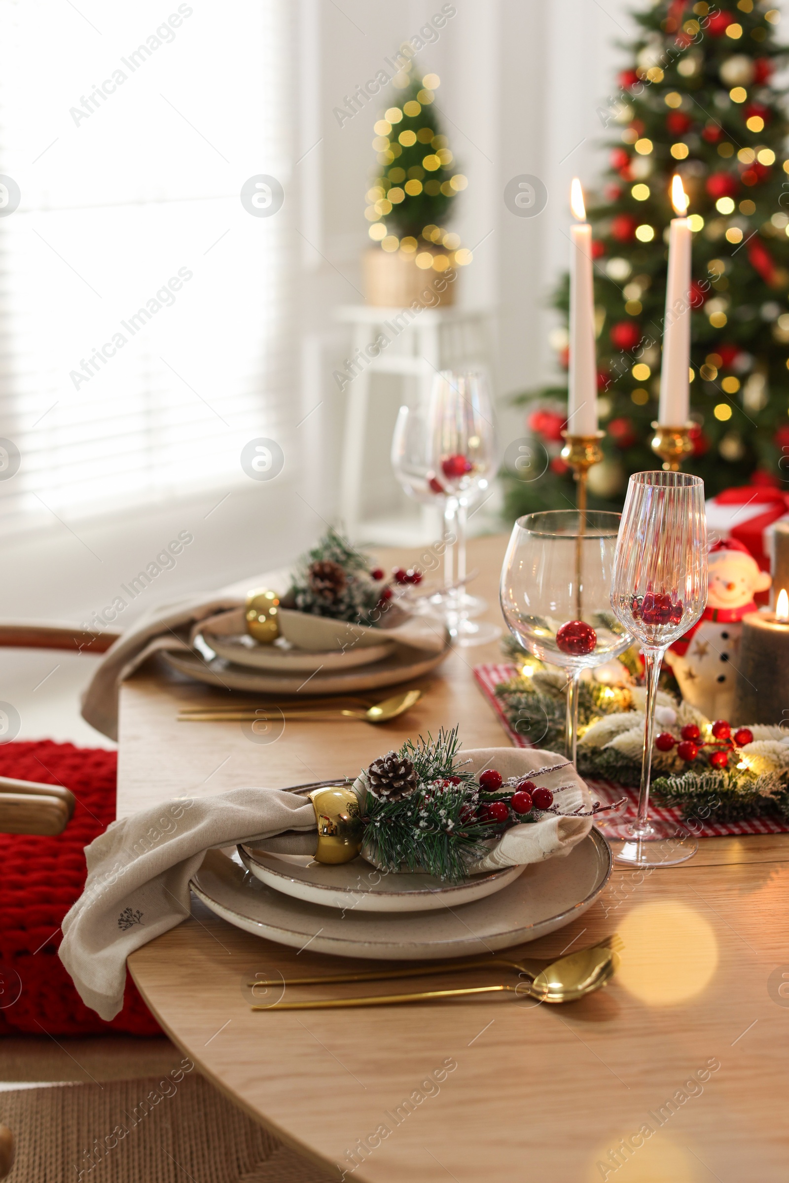 Photo of Christmas celebration. Festive table setting with dishware, glasses and decor in room