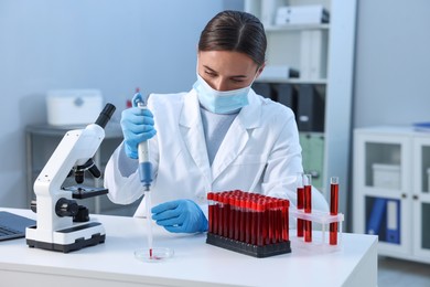 Photo of Laboratory testing. Doctor dripping blood sample into Petri dish at table indoors