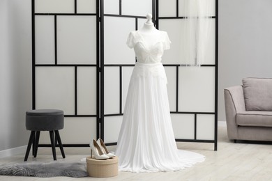 Photo of Beautiful wedding dress on mannequin and shoes in boutique