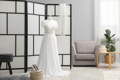 Photo of Beautiful wedding dress on mannequin and shoes in boutique