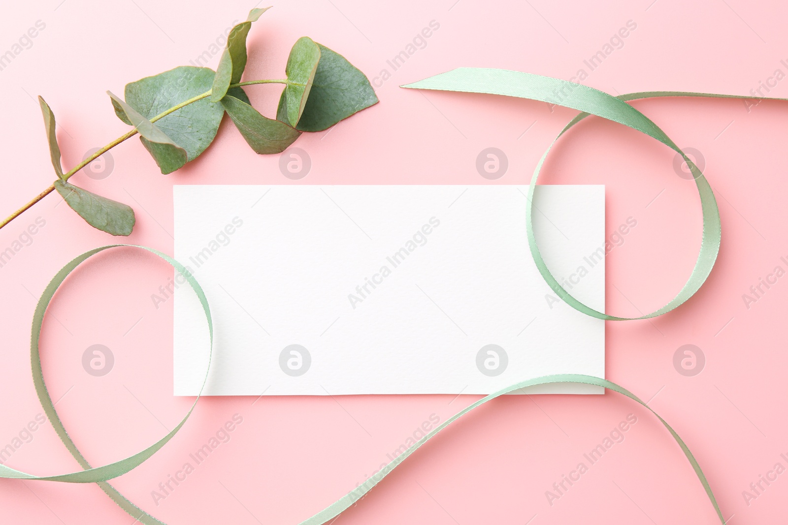 Photo of Blank card, ribbons and eucalyptus branch on pink background, flat lay