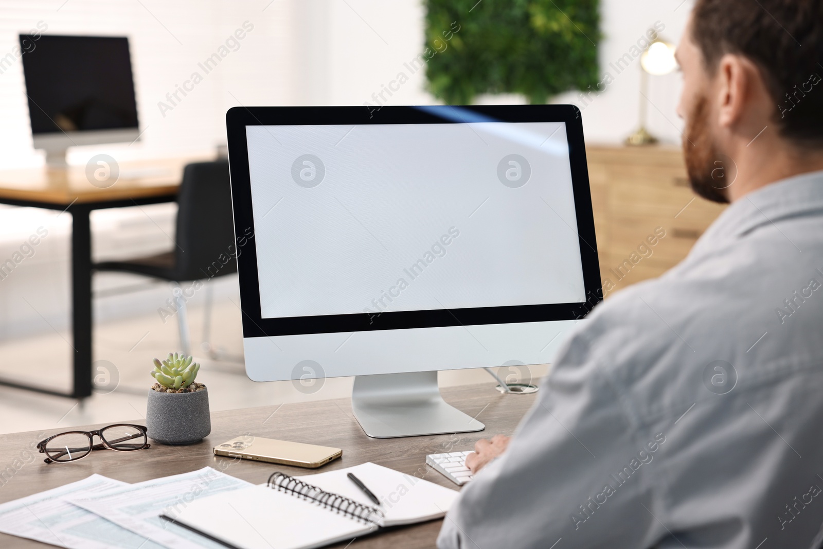 Photo of Man working on computer at table in office, closeup