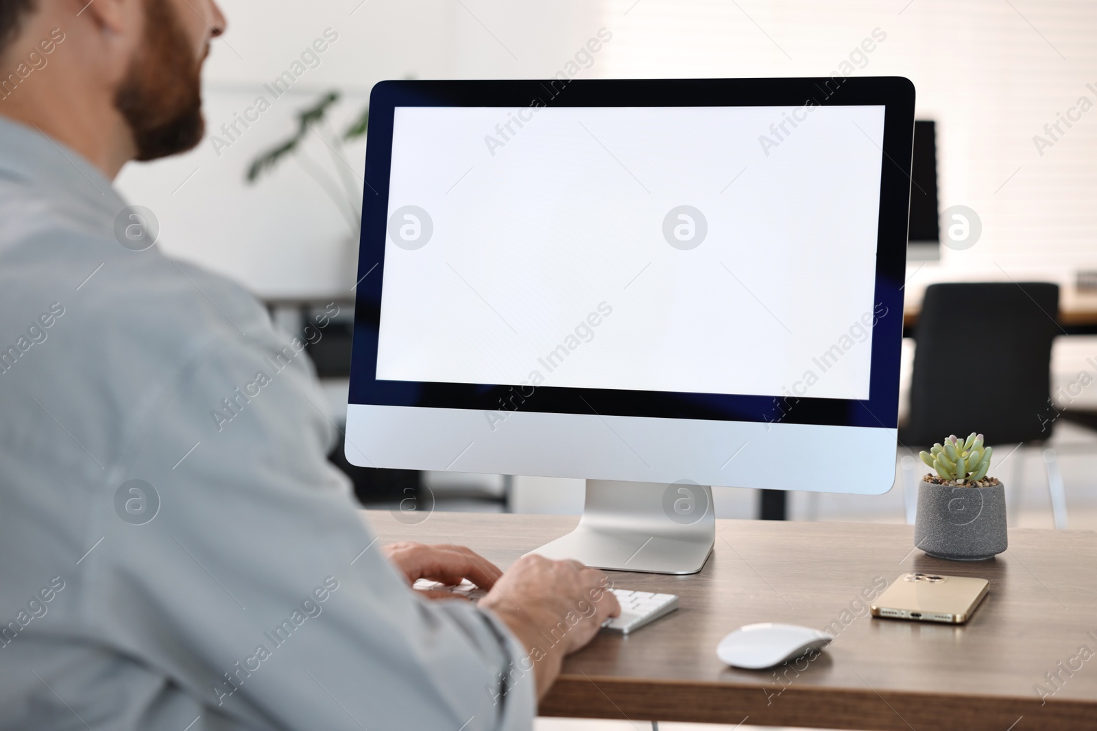 Photo of Man working on computer at table in office, closeup