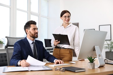 Photo of Colleagues working with computer at desk in office