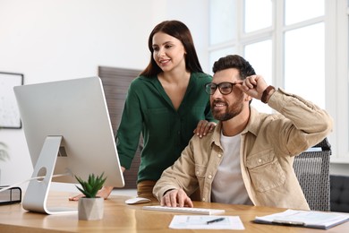 Colleagues working with computer at desk in office