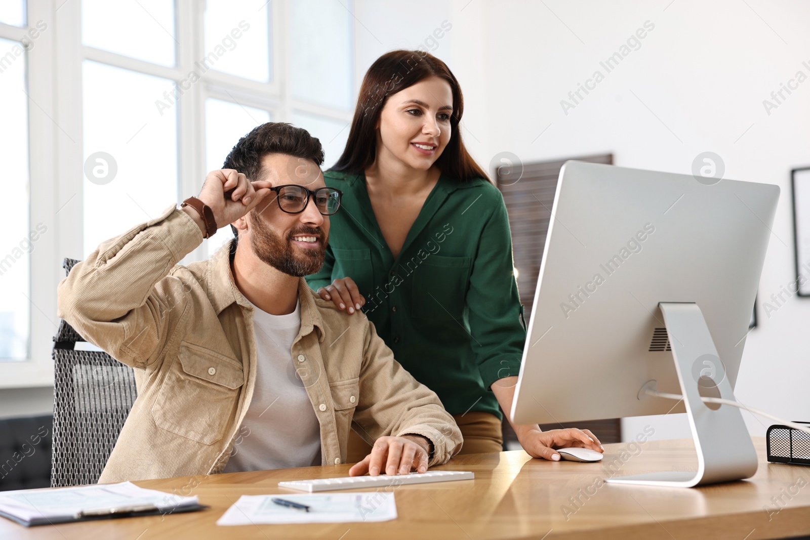 Photo of Colleagues working with computer at desk in office