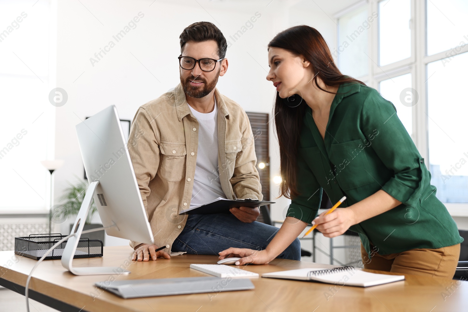 Photo of Colleagues working with computer at desk in office