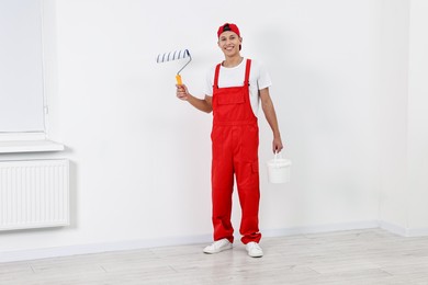 Photo of Smiling handyman with roller and paint indoors