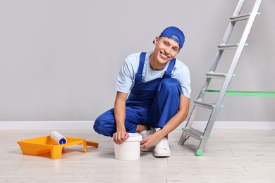 Photo of Smiling handyman preparing to painting wall indoors