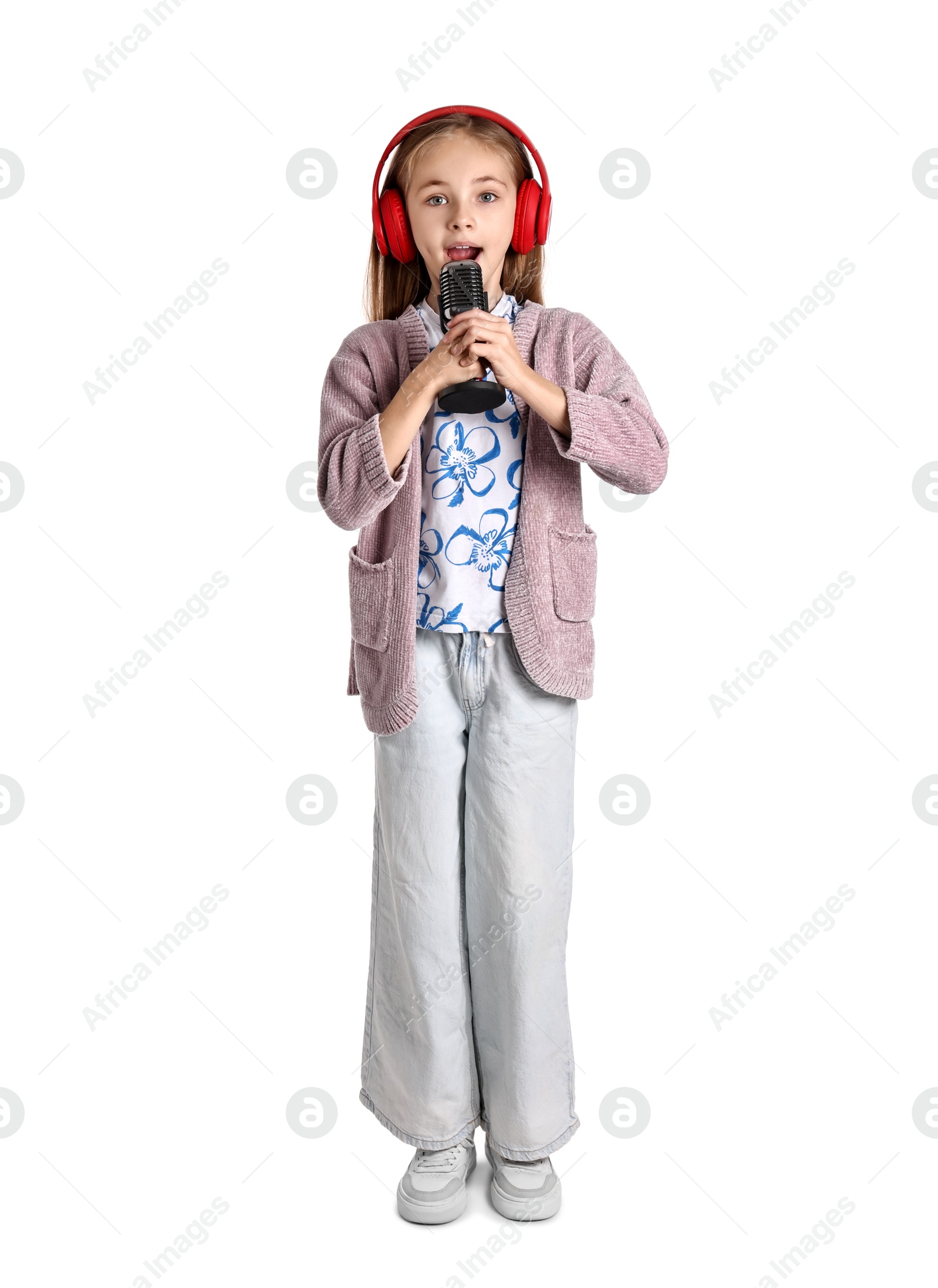 Photo of Little girl with microphone and headphones singing on white background