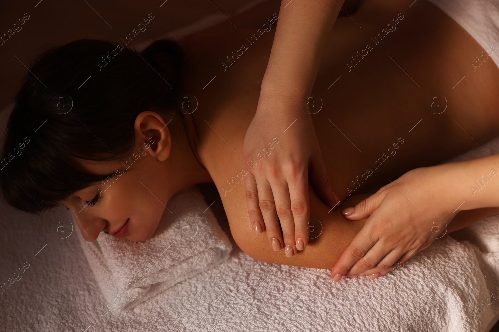 Photo of Young woman receiving massage in spa salon