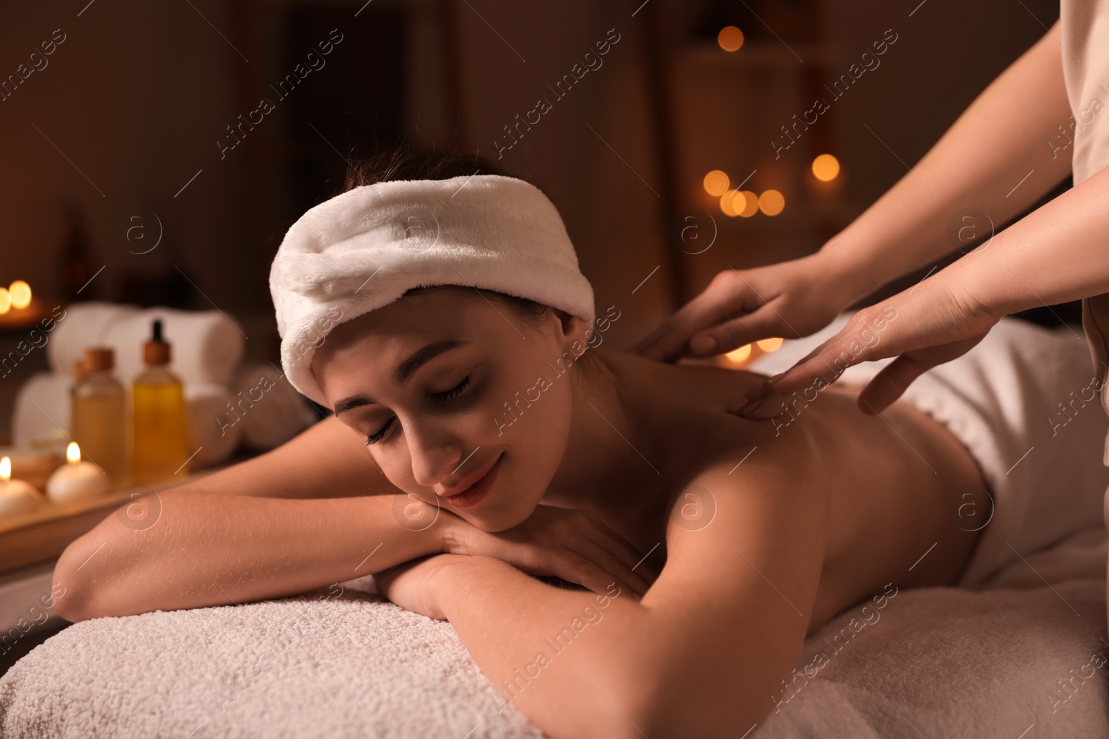 Photo of Young woman receiving back massage in spa salon