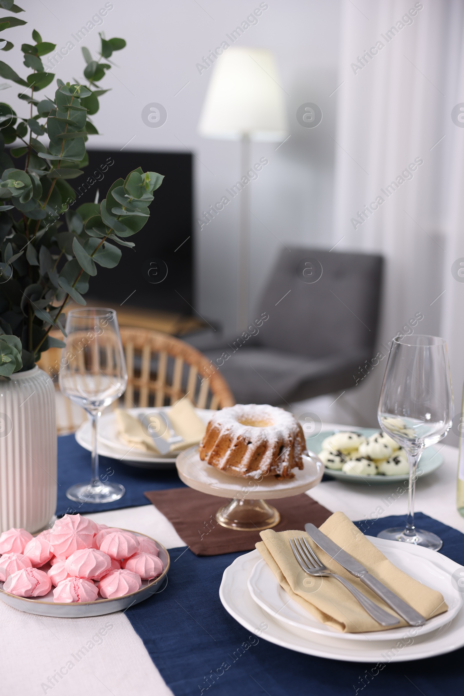 Photo of Festive table setting with dishware, desserts and glasses indoors