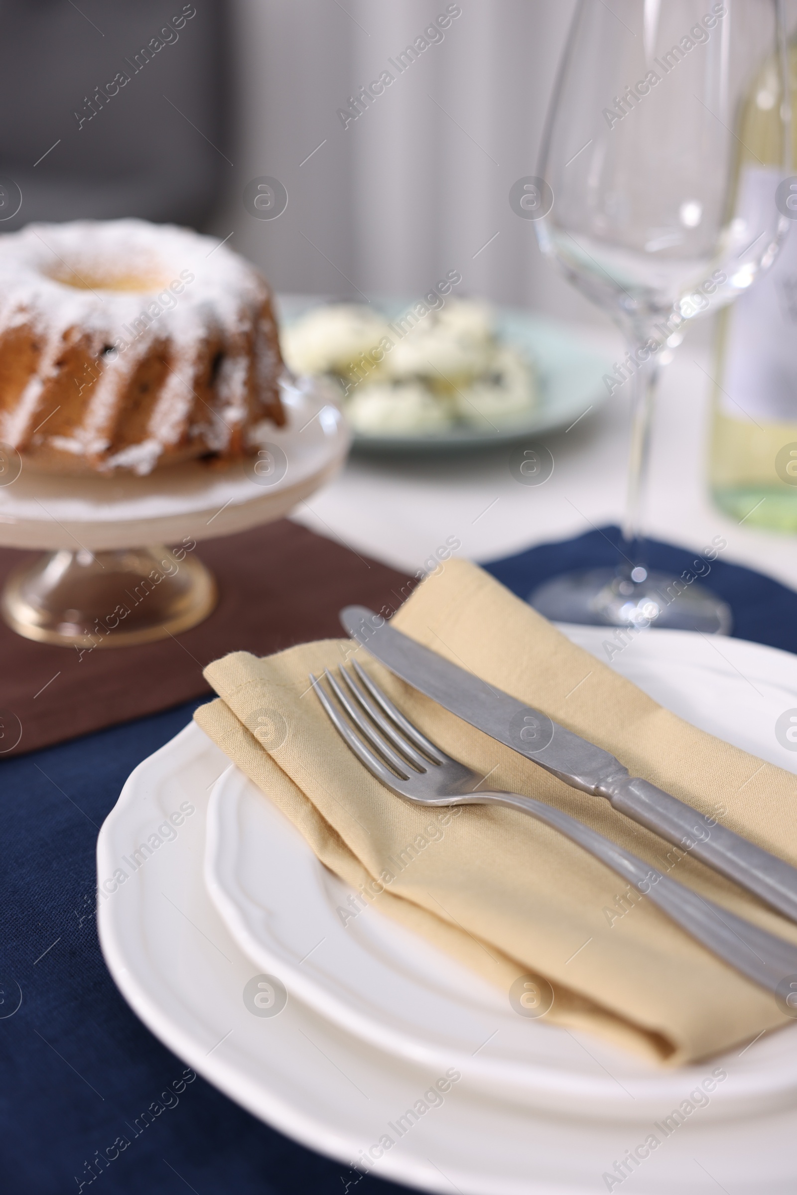 Photo of Festive table setting with dishware, cutlery, glass and dessert indoors, closeup