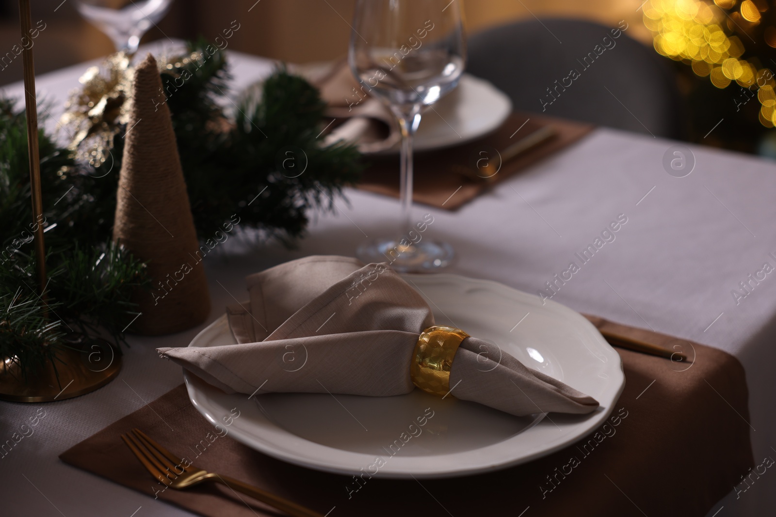 Photo of Christmas table setting with dishware, cutlery, napkin and decor indoors, closeup