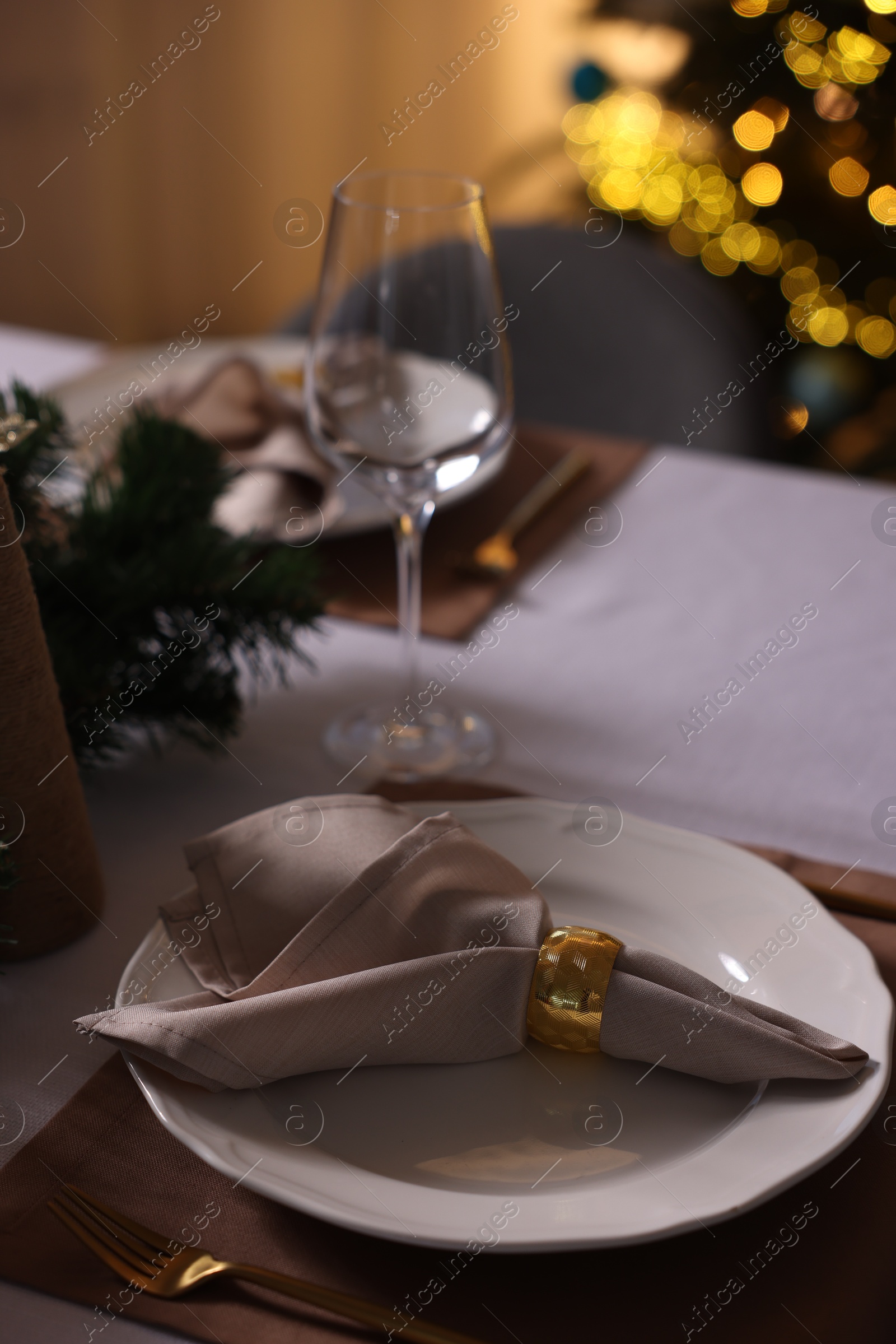 Photo of Christmas table setting with dishware, cutlery, napkin and decor indoors