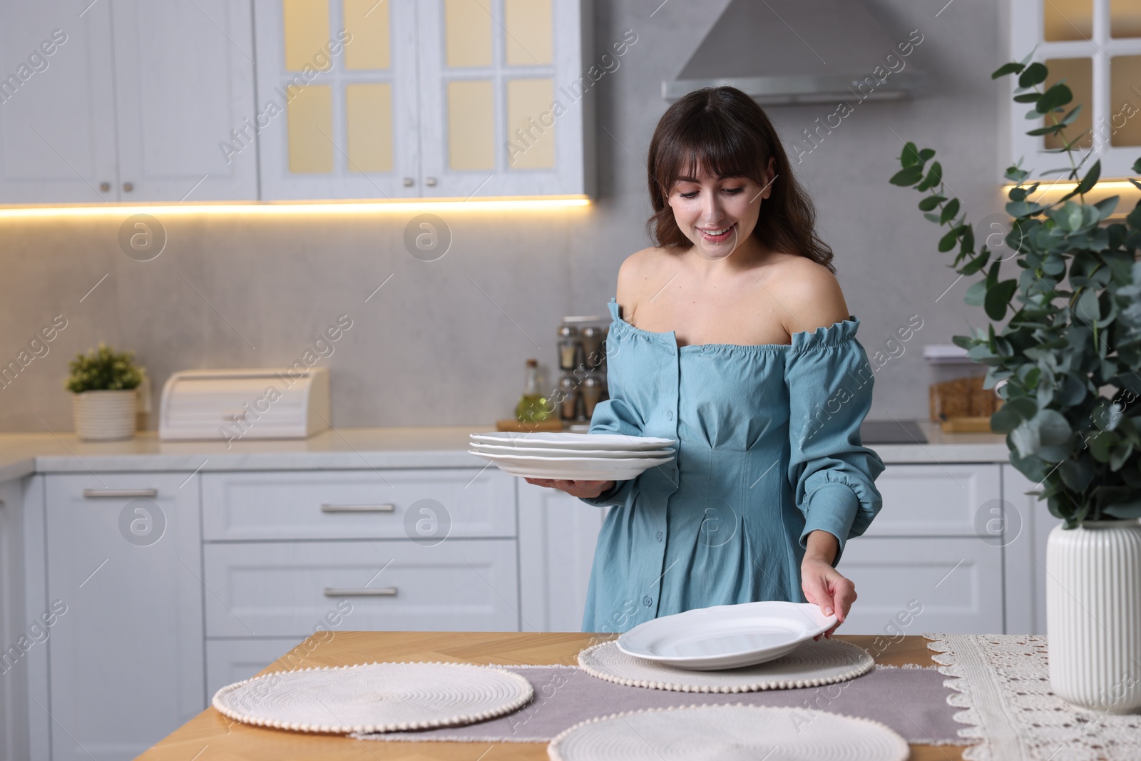 Photo of Woman setting table for dinner at home, space for text