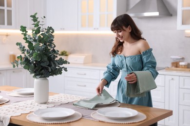 Woman setting table for dinner at home