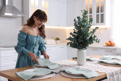 Woman setting table for dinner at home